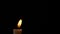 Slow motion closeup burning single candle flame isolated on black background