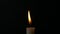 Slow motion closeup burning single candle flame isolated on black background