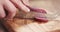 Slow motion closeup female slicing thin salami sausage