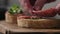 Slow motion closeup man hands making bruschetta with pesto and salame