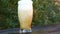 Slow motion closeup pouring beer with foam and bubbles in glass on wooden table