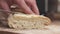Slow motion closeup slicing fresh baguette on cutting board