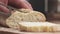 Slow motion closeup slicing fresh baguette on cutting board