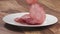 Slow motion closeup thin salami slices falling on white plate