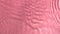 Slow motion closeup water surface texture splash and ripples on pink background