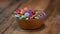 Slow motion, Colorful candies in a wooden bowl case isolated on wood background