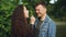 Slow motion of cute couple husband and wife having fun in the forest, girl is blowing dandelion blowball in man`s face