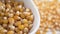 Slow Motion Drop the uncooked corn seeds into a white popcorn bowl.