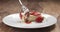 Slow motion of eating strawberry cheesecake with fork on wood table