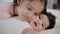 Slow motion of Elder sister kissing newborn baby while lying on bed, adorable girl kiss cheeks toddler with love and care. cute li
