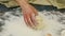 Slow motion of female hands throw small piece of yeast dough into pile of white flour