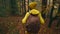 slow motion female hiking in forest in Atumn. adventurous woman in yellow outdoor wear with backpack hiking on trail