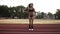 Slow motion of fit, muscular woman in black bikini jumping, using skipping rope in stadium outdoors. Front view
