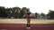 Slow motion of fitness-woman in black bikini jumping, using skipping rope in stadium outdoors. Front view