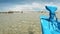 Slow motion floating blue fishing boat stem view over clear sea water in a bay among mangroves, beaches and mountains in the backg