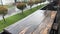 Slow motion footage of rain falling down on wooden table of cafe and asphalt road in summer. Downpour rapid footage