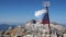 Slow motion footage of a tattered Russian flag developing in the wind. In the background is a blue sky and snowy mountains. The co