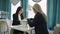 A slow motion general shot of a blonde beautician making a manicure for a client and listening to her speech