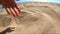 Slow motion. Girl picks up handful of sand in her palm and sprinkles