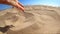 Slow motion. Girl picks up handful of sand in her palm and sprinkles