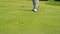 Slow motion golfer putting golf ball into hole