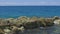 Slow motion. Gorgeous view of waves braking on stones. Turquoise water of Atlantic ocean and big rocks on blue sky background. W.