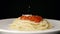 SLOW MOTION: Grated parmesan falls on a hot spaghetti with sauce