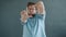 Slow motion of guy making focus hand gesture and smiling looking at camera on gray background