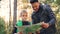Slow motion of happy family father and cute son looking at map and talking during hike in forest in autumn. Trees