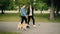 Slow motion of happy modern young people walking cute small dog in park and laughing. Girl and guy are wearing modern