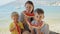 Slow motion of a happy mother and her two boys share laughter and sweet watermelon on a beachside picnic. Family