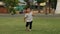 Slow-motion of happy toddler girl running on grass field in park