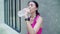 Slow motion - Healthy beautiful young Asian runner woman drinking water because feel tired after running on street in urban city.