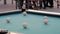 Slow motion: hitting pool ball on teal billiards table - close up