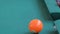 Slow motion: hitting pool ball on teal billiards table - close up