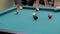 Slow motion: hitting pool balls on teal billiards table - close up