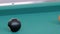 Slow motion: hitting pool balls on teal billiards table - close up