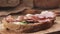 Slow motion of italian speck put on rustic bread with arugula and ricotta cheese