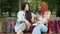 Slow motion of joyful teenagers chatting on bench in park with shopping bags