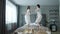 Slow motion of joyful youth girl and guy dancing on hotel bed relaxing having fun