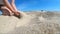 Slow motion. Low angle. Girl picks up handful of sand in her palm