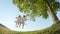 SLOW MOTION LOW ANGLE: Young boy hugging a little girl swinging on wooden swing