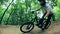 Slow motion of a male cycler riding along forest ramps