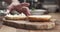 Slow motion man hands spreading cream cheese on bagel on wood board