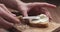 Slow motion man hands spreading cream cheese on baguette slice on wood board