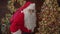 Slow motion of man in Santa costume holding bag walking in room looking at camera