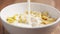 slow motion of milk pour into corn flakes in white bowl