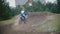 Slow motion: Motocross racer jumping. Rear view of biker on track in rapid shoot