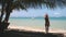 Slow motion ocean beach: woman relax on lounger at palm shadow. Pretty girl tan on sun, hammock