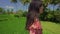 Slow motion outdoors lifestyle shot on young beautiful and happy Asian Chinese woman in stylish Summer dress walking on rice field